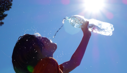 Child pouring water onto his face.